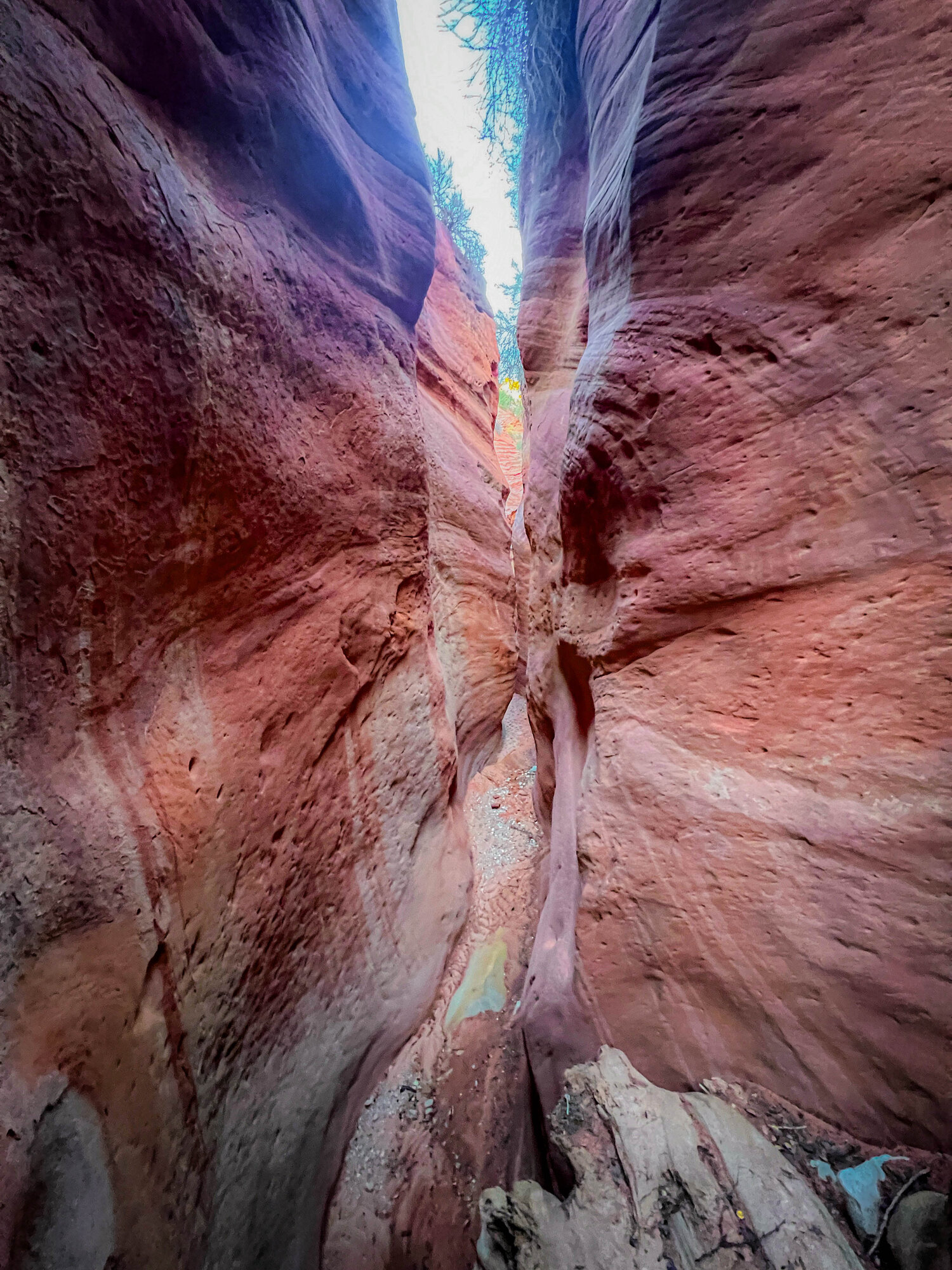 A hiker in the narrow, glowing upper section of the Peekaboo slot canyon