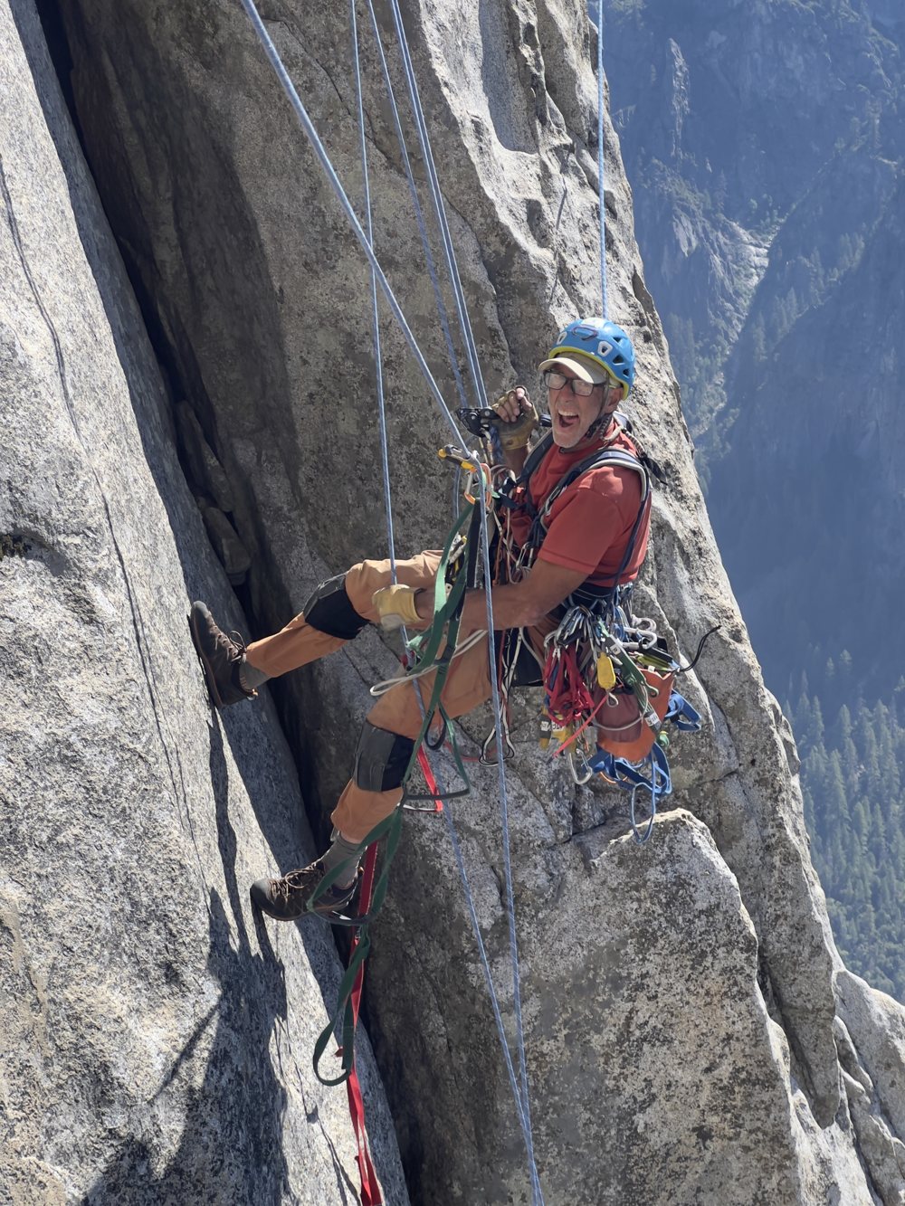 Paul Gagner on a rope high on El Capitan, smiling, with Yosemite Valley behind him